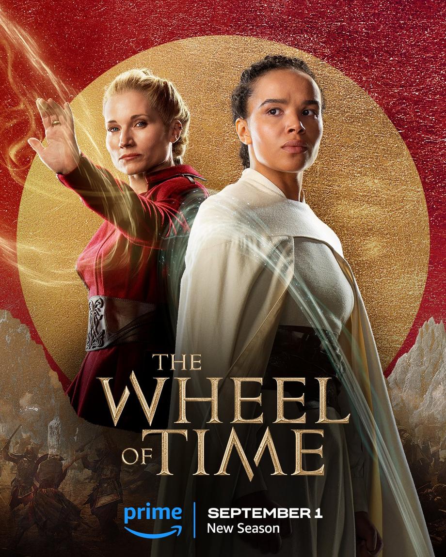 A large gold leaf-textured circle sits atop a red foil background. The jutting peaks of mountains are beneath the circle, with people locked in battle in front of the range. Two characters are featured centered in the image. In the foreground on the right, Nynaeve is featured in a medium shot. Her hair is pulled back; she wears a creamy white cloak over a belted dress; and an illuminated weave wraps around her. Behind her to the left stands Liandrin, also shown in a medium shot. Her hair is pulled back; she wears a red dress with a belt; and her left arm is extended as she channels the One Power as illuminated weaves wrap around her hand. Golden text in the lower center reads, “The Wheel of Time.” At the bottom, the blue Prime Video logo sits next to white text that says “September 1, New Season.”